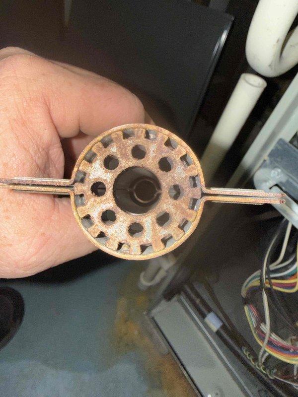 Performed scheduled heating maintenance on two furnace units, including borescope inspection of the heat exchanger and internal ducting and examination of the burner assembly. Found heavy corrosion and flaking rust on a burner flame-spreader component and minor rust spotting at a heat exchanger seam, and documented both conditions with photos for further evaluation and recommended repair.