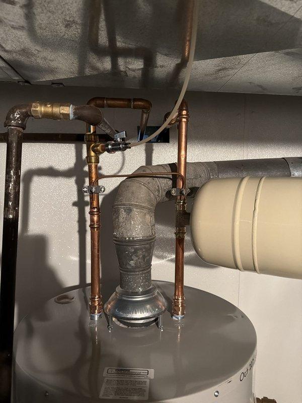 Replaced the cast iron main drain stack with PVC from the basement up to the access behind the tub, installed a new toilet flange, and tied back into the existing tub and lavatory drains. Installed a new 40-gallon short water heater with code-required upgrades, including a new expansion tank and updated flue and supply connections. Opened the basement landing wall to gain access for the stack replacement.