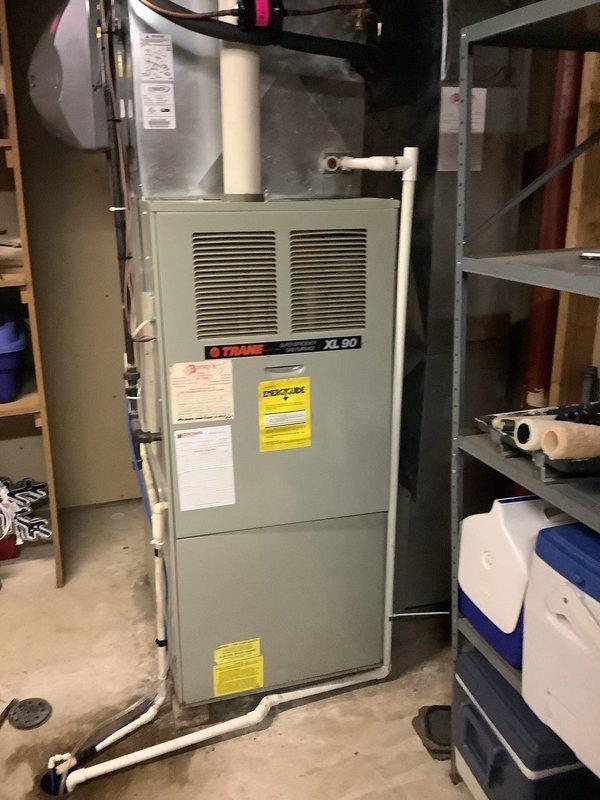 Performed an on-site replacement estimate for a 35-year-old Trane XL 90 gas furnace with a Carrier-branded humidifier mounted on the supply plenum. Inspected the unit, condensate drain piping, PVC venting, and surrounding ductwork, and documented the equipment with photos; no frost, rust, or significant damage was observed, though the unit's age warrants evaluation for replacement.