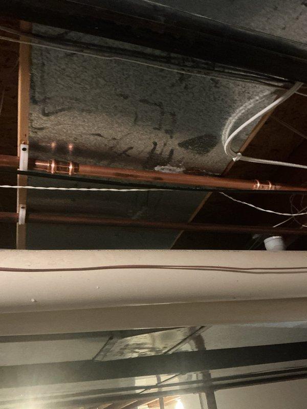 Located and repaired a leak in the copper supply line running from the water heater toward the master bedroom, where corrosion, verdigris, and mineral buildup had compromised the pipe. Removed the failed section and replaced it with new copper using soldered fittings, then confirmed the repair was secure and leak-free under pressure. Protected the work area with shoe covers and containment buckets throughout the repair.