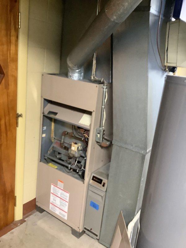 Performed an on-site replacement estimate for a 30+ year old gas-fired furnace, inspecting the burner assembly, gas valve, wiring, and flue piping, and noting general wear with discoloration on the flue pipe consistent with the unit's age. Reviewed the existing sheet metal plenum and ductwork, refrigerant line set, gas piping, and condensate/PVC routing to evaluate compatibility with a new system, and documented the installation with photos for the second-opinion evaluation.