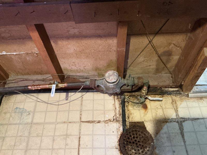 Coordinated a municipal water shutoff at the street, then cut out the leaking main shutoff valve ahead of the water meter and soldered in a new brass ball valve in its place. Installed a second new ball valve downstream of the meter, restoring dual isolation points on both sides of the meter. Existing meter spuds were left in place, and the corroded piping and fittings near the meter were not part of the scope of work.