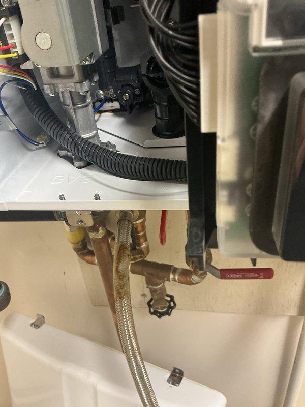 Performed a descale flush of the tankless water heater by isolating the unit at the service valves and circulating descaling solution through the heat exchanger to remove mineral buildup, then flushed the system with clean water and restored normal operation. Removed the saddle valve feeding the humidifier, which had not been addressed during the original installation, and capped the connection to eliminate a potential leak point. Noted corrosion and rust staining on the braided flex connector and brass fittings, which should be monitored for future replacement.