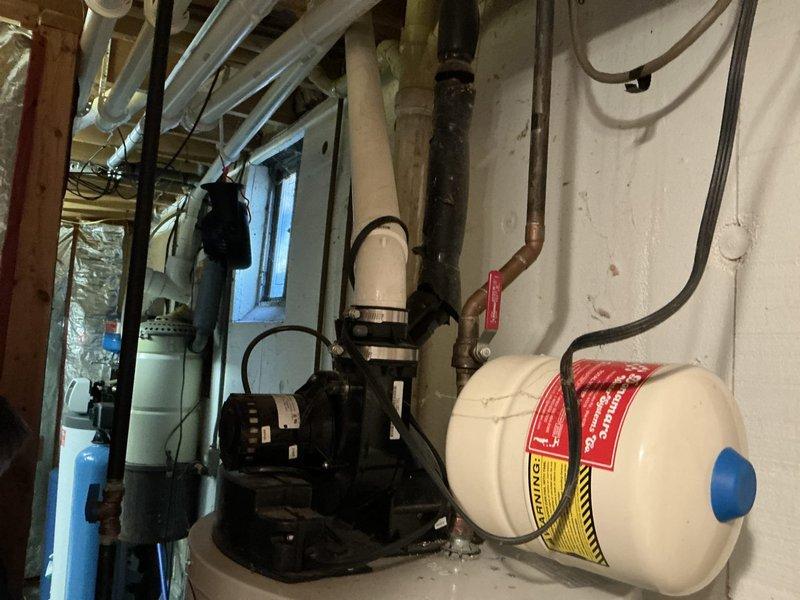 Performed an on-site estimate for replacing the existing power-vent tank-style water heater with a tankless unit, and evaluated relocating a furnace to the garage. Inspected the existing Smith water heater, PVC exhaust venting, expansion tank, copper supply piping with isolation valve, condensate/drain routing, and electrical connections, and found no visible leaks, rust, or damage. Documented the mechanical room layout with photos to determine gas, venting, and water line requirements for the tankless installation.