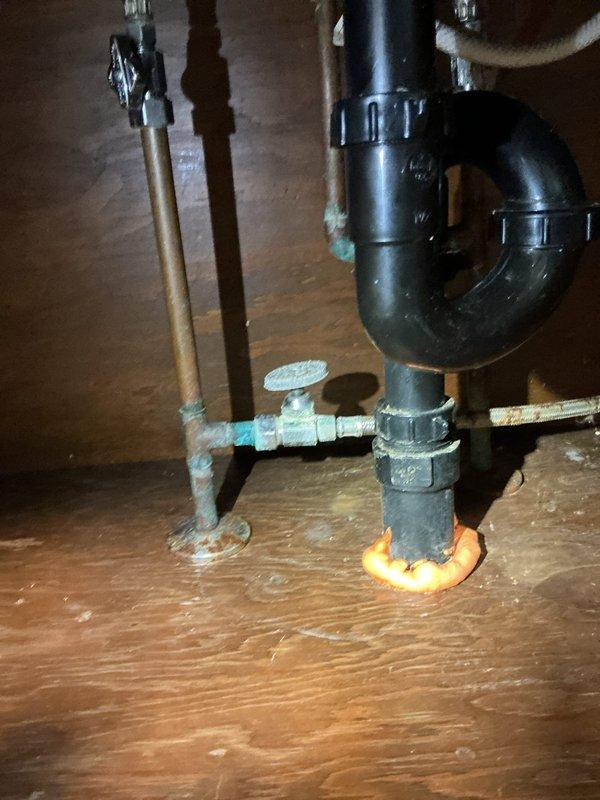 Responded to a callback for leaking and dripping at a recently installed utility sink and two faucets. Inspected the under-sink supply and drain assemblies and found heavy verdigris corrosion and mineral buildup at the soldered copper joints, angle stop valve, and base flange, along with slip-joint connections on the P-trap and flexible supply lines as potential leak points. Documented all findings with photos.