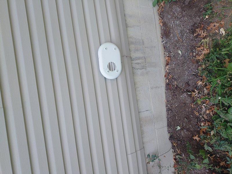 Located the detached louvered exterior vent cover from the recently installed furnace and reinstalled it on the exterior wall at the combustion air/vent termination, securing it with screws. Verified the PVC intake and exhaust terminations were properly seated in the mounting plate and free of obstruction.