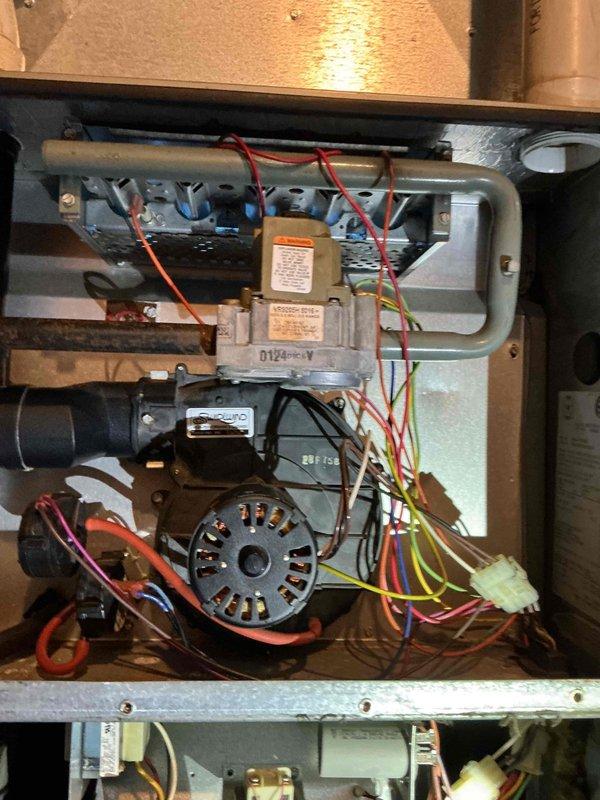 Responded to a no-heat call with no furnace response on a thermostat call for heat. Inspected the furnace cabinet and burner compartment, including the draft inducer assembly, gas valve, wiring harness, and control components, and used an inspection camera to examine the heat exchanger and internal cavity areas, which showed rust and corrosion staining. Diagnosed the cause of the no-heat condition and documented the findings with photos.