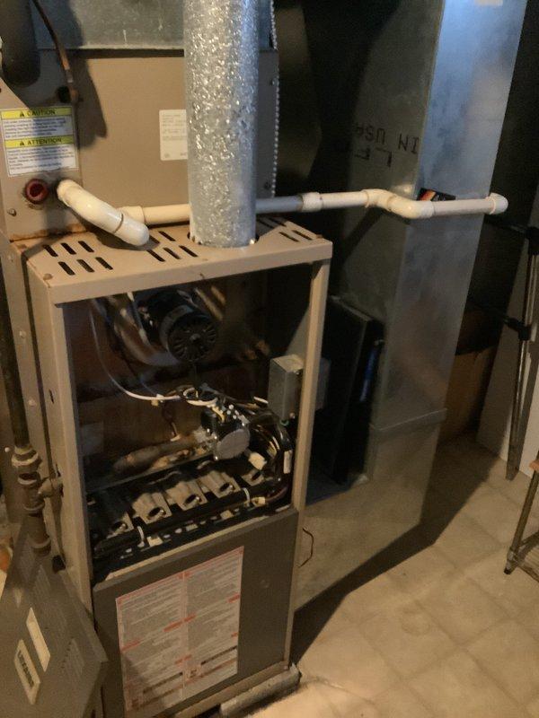 Performed an on-site evaluation of a 25-year-old gas furnace in the basement to provide a replacement estimate. Inspected the open burner compartment, gas valve and igniter assembly, blower motor, wiring, flue venting, PVC condensate/intake piping, and supply plenum, documenting rust and corrosion on the burner and gas valve components along with general age-related wear. Documented the existing equipment configuration and noted the customer's budget constraints so replacement and assistance options can be reviewed.
