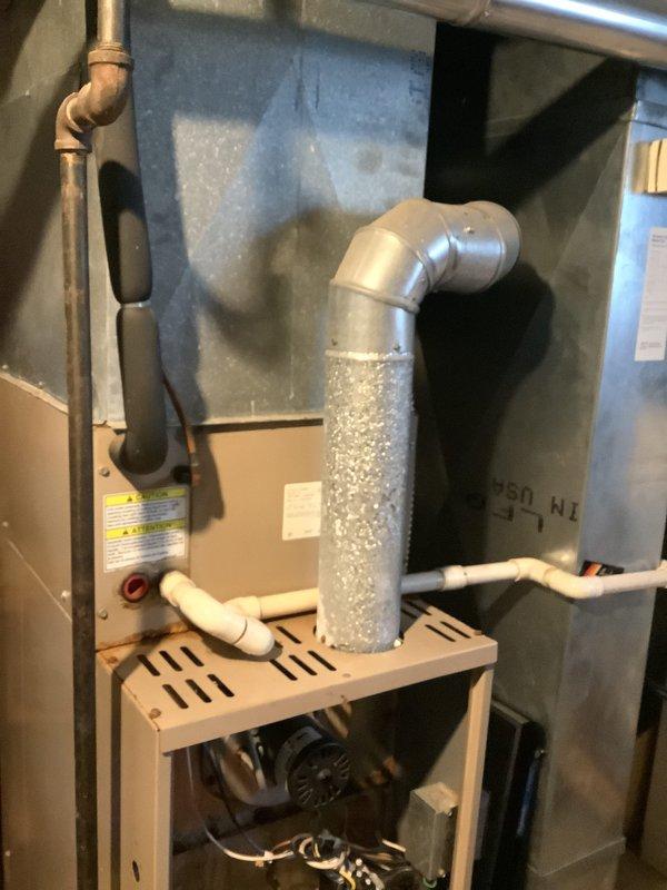 Performed an on-site evaluation of a 25-year-old gas furnace in the basement to provide a replacement estimate. Inspected the open burner compartment, gas valve and igniter assembly, blower motor, wiring, flue venting, PVC condensate/intake piping, and supply plenum, documenting rust and corrosion on the burner and gas valve components along with general age-related wear. Documented the existing equipment configuration and noted the customer's budget constraints so replacement and assistance options can be reviewed.