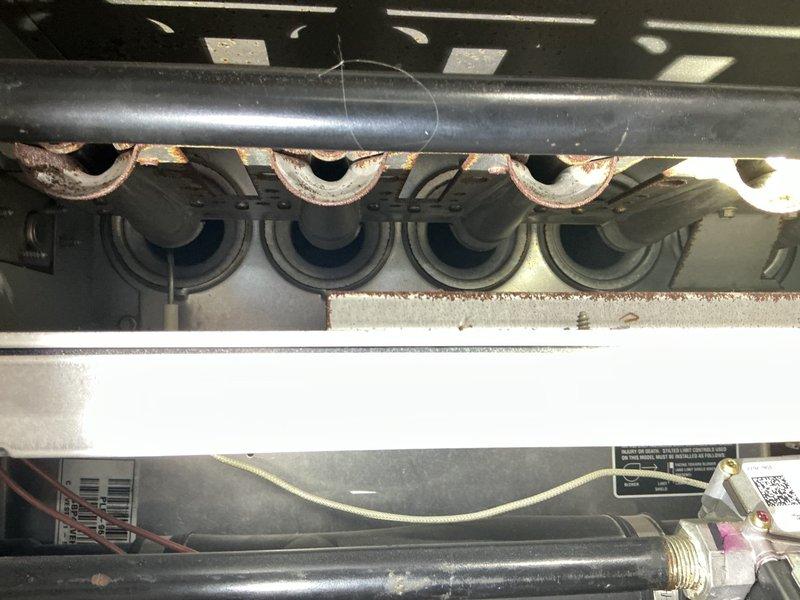 Performed annual heating tune-up on a 16-year-old gas furnace, inspecting the burner assembly, gas valve connections, and wiring with the system operating normally. Documented significant rust and corrosion on the heat exchanger tube inlets and burner compartment brackets, and photographed and marked the affected areas, recommending further heat exchanger evaluation due to the age of the unit and visible deterioration.