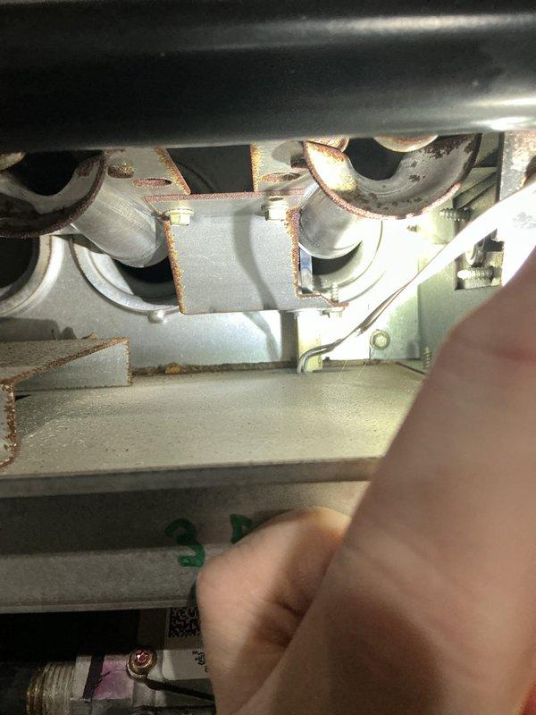 Performed annual heating tune-up on a 16-year-old gas furnace, inspecting the burner assembly, gas valve connections, and wiring with the system operating normally. Documented significant rust and corrosion on the heat exchanger tube inlets and burner compartment brackets, and photographed and marked the affected areas, recommending further heat exchanger evaluation due to the age of the unit and visible deterioration.