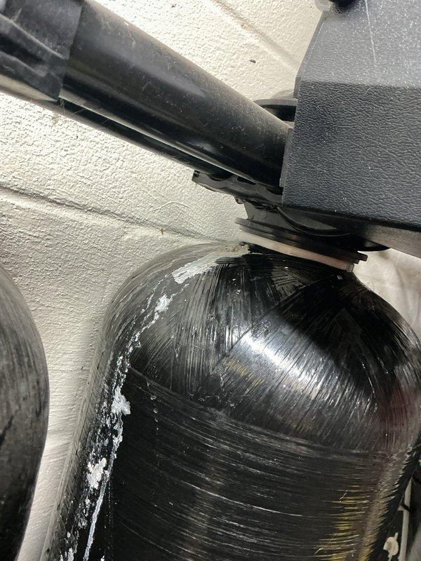 Responded to a leak at the Nelson air injection filter system installed in 2021. Inspection revealed mineral and salt deposit buildup with active seepage along the dome and side of the fiberglass-wrapped pressure tank near the control valve connection. Documented the affected tank and fittings with photos to support evaluation of the tank and valve connection for repair or replacement.