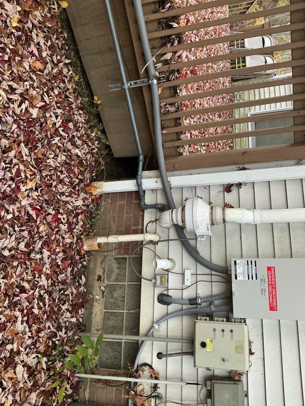 Connected a manometer-style pressure gauge to the exterior gas piping to perform a pressure test, and the gauge held steady at approximately 10 oz/sq in. while the system was monitored. Returned at the end of the day to retrieve the test equipment, with the service disconnect and surrounding conduit and control components remaining intact.