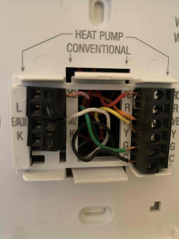 Diagnosed system that was continuously running in auxiliary heat mode despite moderate outdoor temperatures, causing excessive energy consumption (65W auxiliary heat). Inspected thermostat wiring connections and verified proper heat pump/conventional system configuration. Rewired connections at both the outdoor unit and thermostat terminal blocks to restore proper staging sequence, ensuring the system now operates in standard heat pump mode during appropriate temperature conditions.