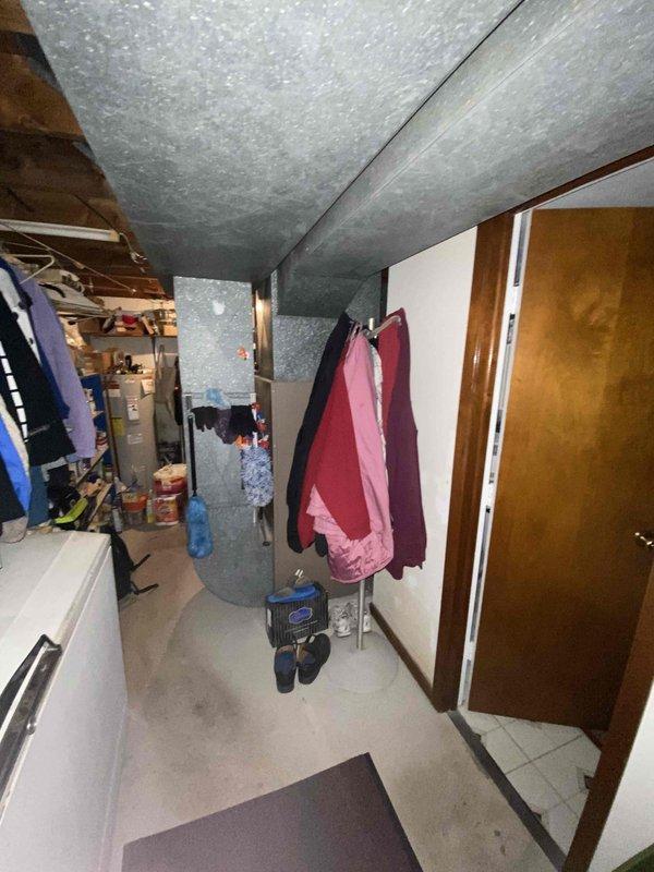 Conducted assessment of obsolete oil furnace system (approximately 60 years old) in confined utility space. General Electric air handler unit observed with extensive metal ductwork covered in gray insulation. System has not received maintenance for approximately 2 years. Recommended full replacement due to equipment age and inefficiency.
