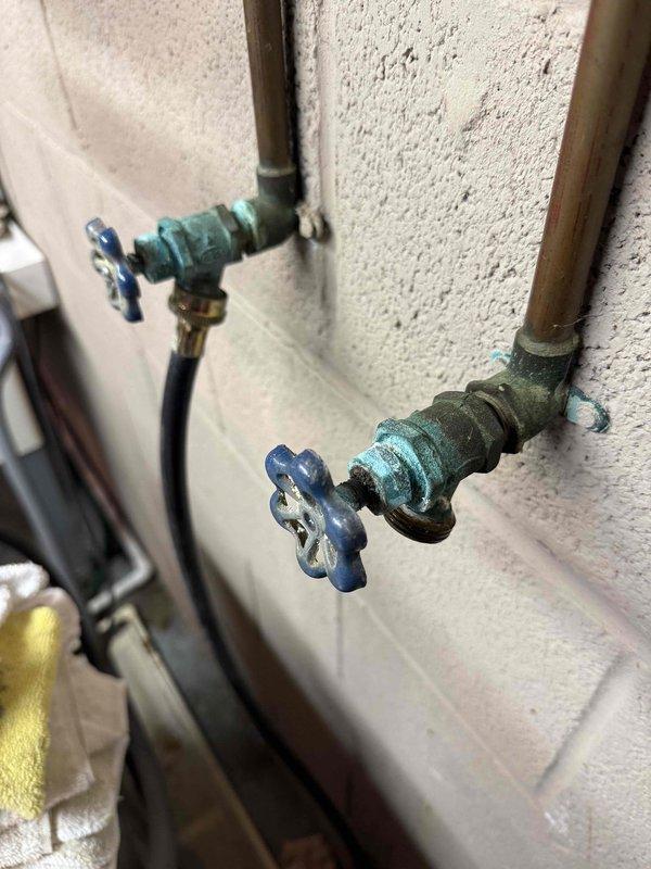 Diagnosed 25-year-old Kenmore water treatment system with complete water flow obstruction. Inspection revealed significant corrosion and mineral buildup on copper supply lines and valves, particularly at connection points where extensive verdigris had developed. Determined system failure due to age-related deterioration and mineral deposits blocking water intake.