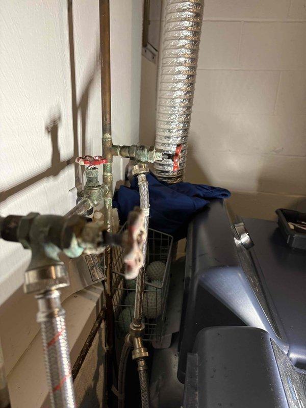 Responded to service call for faucet removal issue. Upon inspection, discovered severely rusted mounting bolts preventing faucet removal. Observed significant corrosion on copper supply lines and mineral deposits on fixtures in the utility area. Work area included access to braided supply lines and connection points in a confined space.