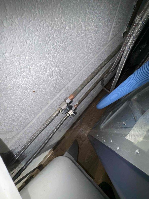 Responded to service call for faucet removal issue. Upon inspection, discovered severely rusted mounting bolts preventing faucet removal. Observed significant corrosion on copper supply lines and mineral deposits on fixtures in the utility area. Work area included access to braided supply lines and connection points in a confined space.