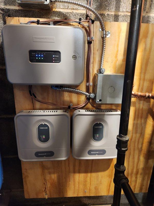 Successfully installed a Peerless Mi-X 03 84% efficiency boiler with three zone valves and WiFi thermostats. System includes Honeywell Home controls mounted on wooden panel with proper electrical connections. Additional plumbing repairs were completed and a new hot water tank was installed with all copper piping properly connected and pressure-tested.