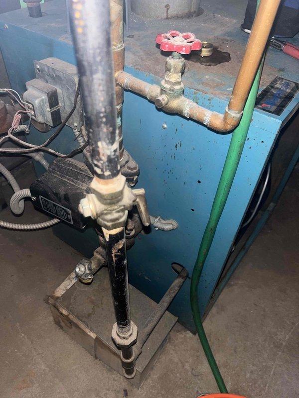 Responded to a no-heat call for a boiler system showing error code $65w AH on the thermostat. Inspection revealed worn valve assembly with surface corrosion on copper components. Serviced the control valve/regulator assembly and cleaned accumulated dirt from connection points. System restored to proper operation after component maintenance.