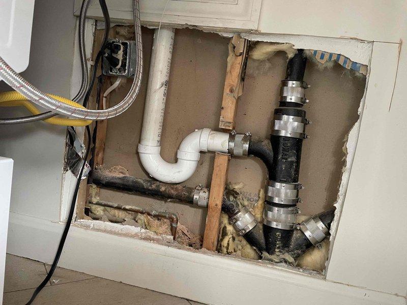 Returned to property to service laundry drain line. Accessed wall cavity to inspect plumbing, identifying a severely deteriorated P-trap with significant black mold/corrosion buildup. Removed damaged P-trap assembly and replaced with new components to restore proper drainage function.