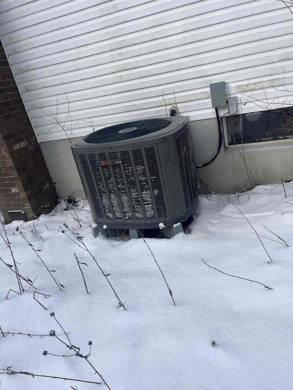 Inspected Trane heat pump system (installed 2021) that was failing to operate in cold temperatures, despite manufacturer specifications indicating operation capability well below 0°F. Found outdoor unit severely restricted by heavy snow accumulation and condenser coil completely clogged with debris, preventing proper airflow. Cleared snow from around unit and cleaned condenser coil to restore proper heat transfer and system operation.