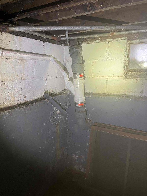 Responded to a water leak issue affecting ceiling. Upon inspection, found moisture damage in basement/crawlspace with standing water present. Located the source at a PVC pipe connection with distinctive orange/red banded valve. Repaired plumbing fixture to stop active leak and prevent further water damage to the property.