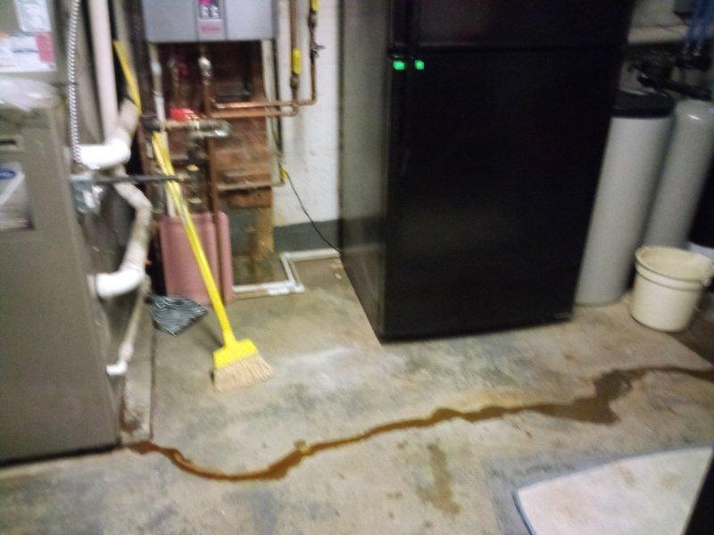 Diagnosed and repaired furnace leak causing system failure, evidenced by water pooling on basement floor and thermostat displaying "Call for Service" error. Restored heating functionality with thermostat now properly maintaining desired temperature (74°) after repair and system reset.