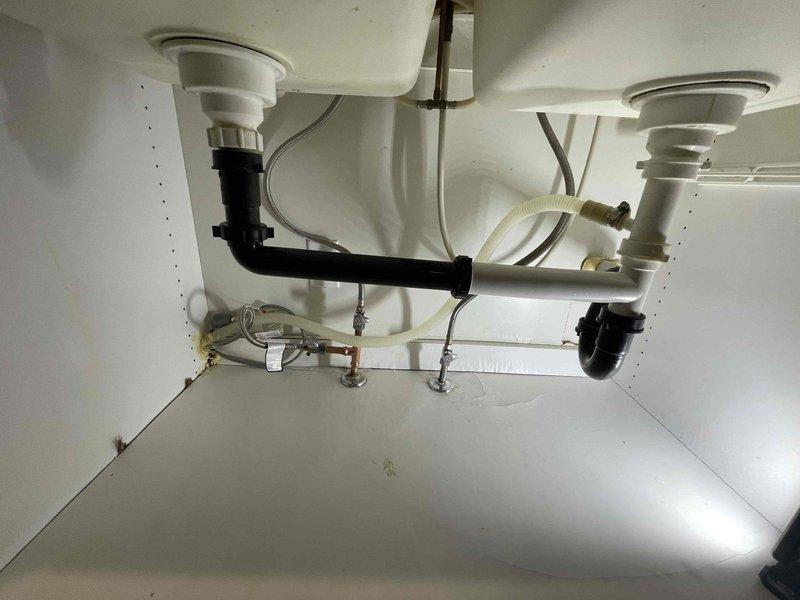Responded to emergency call from Greg Viviani regarding active water leak under sink where a nozzle had blown out. Inspected the sink plumbing system and discovered a failed connection at the P-trap assembly. Replaced the damaged section and verified proper drainage function with no leaks after repair.