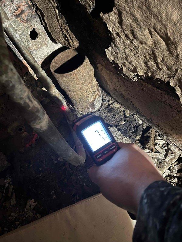 Responded to frozen pipe service call for John Marple. Inspected plumbing system using infrared thermometer to identify frozen sections in confined crawl space. Found significant pipe deterioration and rust on older metal pipes. Thawed affected pipes and noted structural concerns around clay waste pipe with deteriorating brickwork that may require future attention.