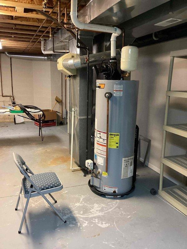 Performed membership service visit to address recurring drainage issue between washer and sink. Inspected and cleared blockage in the drain line. Also examined master bedroom shower valves that required attention, noting dual showerhead configuration (fixed chrome and white handheld) with visible valve control. Inspected water heater and connected PVC plumbing in utility room to ensure proper function and identify any potential issues affecting the overall plumbing system.