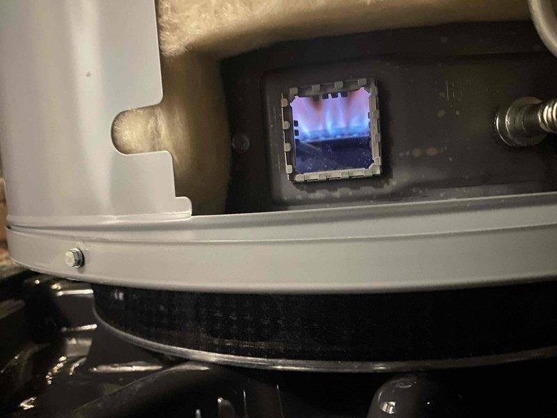 Returned to complete recommended work previously sold by Bruno. Performed service on shower faucet, installing new chrome single-lever handle fixture on tiled wall. Inspected water heater combustion chamber, confirming proper blue flame pattern through viewing port, indicating efficient gas combustion and normal operation.