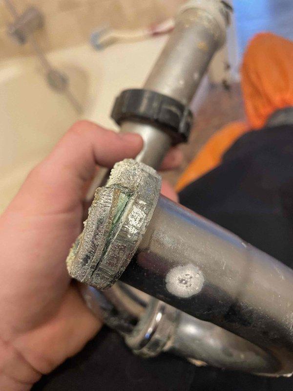 Responded to service call for bathroom sink leaking at the trap. Upon inspection, discovered severely damaged plumbing fixture with a large crack and significant corrosion. Removed and replaced the deteriorated p-trap assembly which showed extensive mineral buildup and calcification at connection points.
