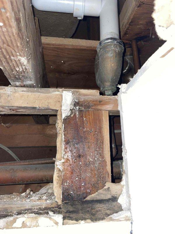 Inspected water leak from kitchen ceiling bulkhead. Upon investigation of the crawlspace, identified aged cast iron drain pipe with significant oxidation and deterioration. Observed moisture damage and discoloration on surrounding wooden joists and structural framing. Repaired compromised section of drain pipe and connections to PVC components to resolve the active leak.