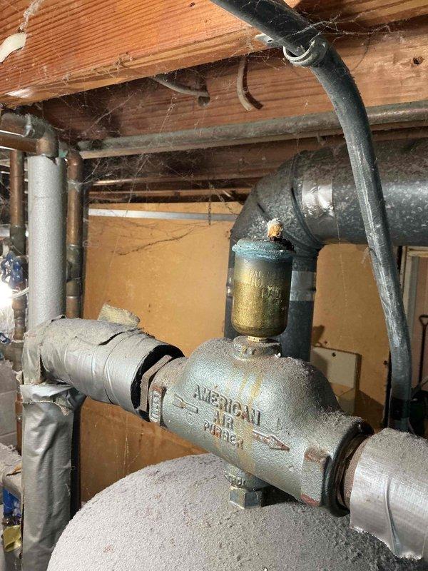Responded to no-heat call for severely outdated oil boiler (1973 vintage) that had been malfunctioning for several years. Inspection revealed deteriorated electrical components with exposed/disorganized wiring connections and significant corrosion on the "AMERICAN" valve assembly and surrounding plumbing. System was beyond economical repair due to extensive age-related wear and component failure.
