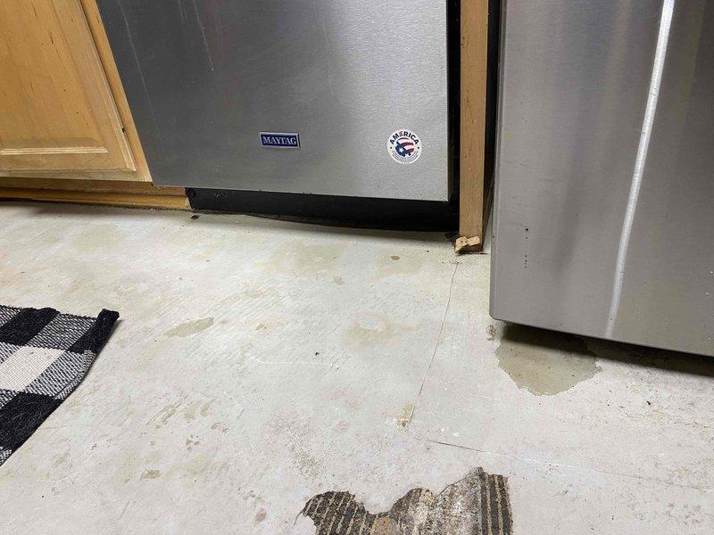 Inspected refrigerator water line leak as requested for insurance documentation purposes. Observed water damage to kitchen floor with visible moisture spots and peeling of laminate/vinyl flooring near the Maytag refrigerator installation junction. Documented evidence of water intrusion at the connection point where the refrigerator's water supply line interfaces with cabinetry.