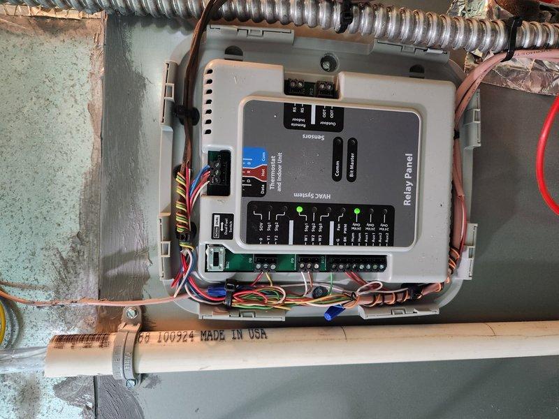 Completed installation of a complete HVAC system with furnace unit, relay panel, and humidifier/air purification component. System includes proper electrical connections with control panel featuring status indicators and multiple terminal connections, along with PVC condensate drainage piping. All components were successfully installed and tested for proper operation.