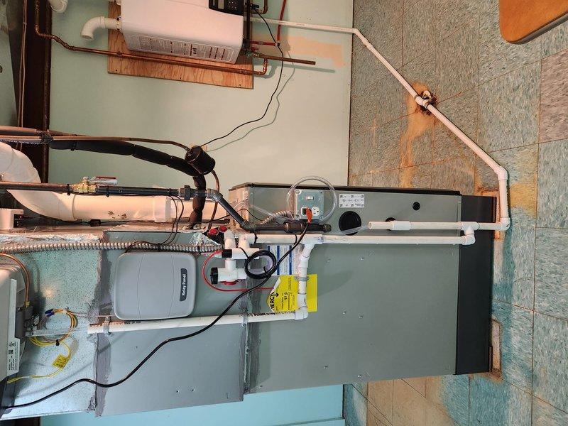 Completed installation of a complete HVAC system with furnace unit, relay panel, and humidifier/air purification component. System includes proper electrical connections with control panel featuring status indicators and multiple terminal connections, along with PVC condensate drainage piping. All components were successfully installed and tested for proper operation.