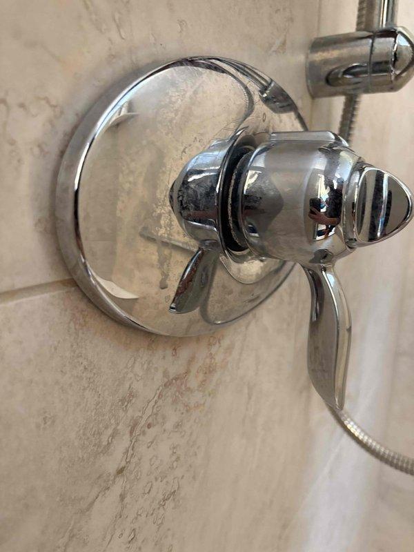 Responded to callback service request for persistent shower head leakage originally serviced by technician Bruno. Inspected chrome shower valve assembly and handle mechanism on tiled wall. Found mineral deposits causing improper sealing. Cleaned valve components and replaced deteriorated internal seals to resolve the continuous dripping issue.