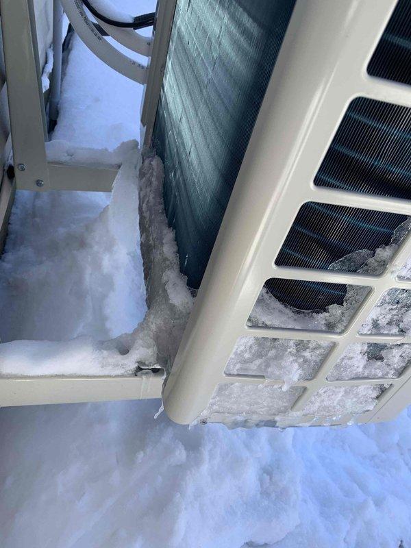 Responded to service call for mini split heat fan malfunction. Discovered outdoor unit heavily encased in snow and ice buildup, significantly obstructing ventilation grills and restricting proper airflow. Cleared accumulated snow/ice from unit, inspected internal components including sensors and heat exchanger coils, and restored system to normal operation.
