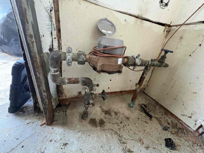 Responded to service call for frozen pipes and no heat. Inspected water meter installation and associated plumbing system showing signs of age and deterioration. Identified and addressed frozen pipe sections, ensuring proper water flow restoration. Confirmed functionality of the system with red shut-off valve and verified no active leaks in the copper and brass plumbing assembly.