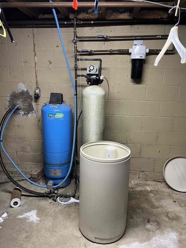 Responded to service call for water softener maintenance. Upon inspection, found salt tank completely empty ("bone dry") and evidence of mineral buildup. Refilled salt tank, performed system check, and verified proper operation of the water treatment system including associated plumbing fixtures.