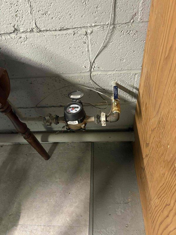 Responded to service call for frozen pipes previously identified by another plumber. Inspected water meter assembly and associated copper supply lines mounted on concrete block wall. Weather conditions with significant snowfall confirmed environmental factors contributing to pipe freezing issue.