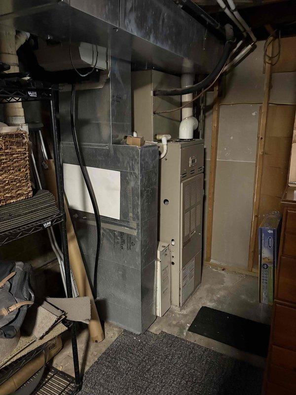 Conducted assessment of 30-year-old furnace system with random failure issues. Inspection revealed aging HVAC infrastructure with deteriorated ductwork connections and outdated components in basement utility area. Recommended complete system replacement to address reliability concerns and improve efficiency, including new furnace unit and proper integration with existing A.O. Smith water heater setup.