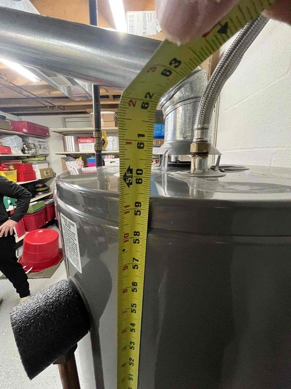 Conducted inspection of existing 50-gallon gas water heater with standard atmospheric venting. Measured tank dimensions and vent pipe diameter (approximately 7-8 inches) to assess replacement options. Customer is considering upgrade to more energy-efficient model; provided information on high-efficiency alternatives.