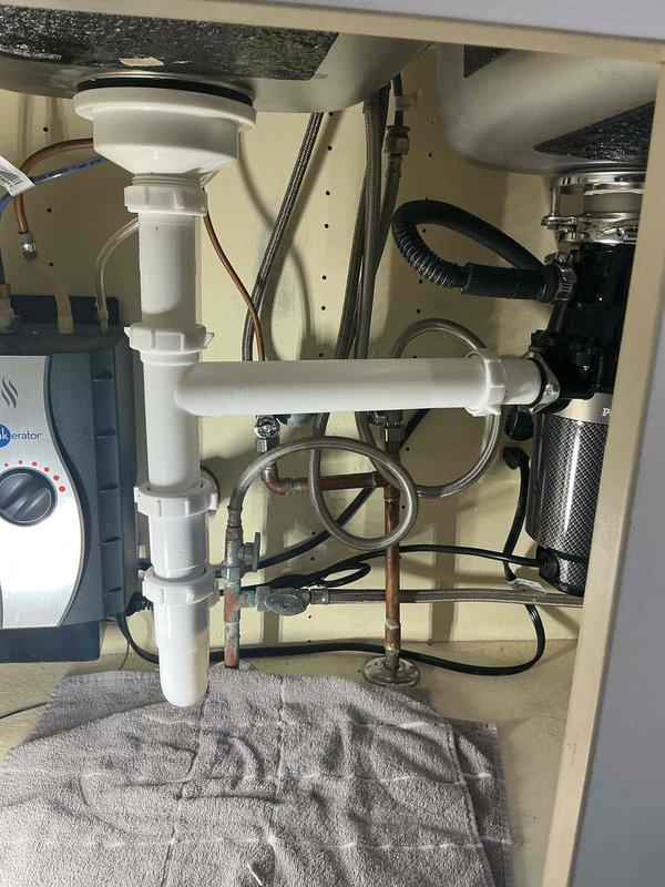 Responded to kitchen sink leak call. Upon inspection, identified water leakage from under-sink plumbing assembly. Serviced the P-trap connection and drain pipe assembly, ensuring proper sealing at all connection points. Checked garbage disposal unit connections for integrity. All components now functioning properly with no active leaks.