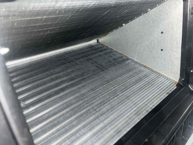 Inspected 1-year-old heat pump system responding to customer complaint of wet dog odor during defrost cycles. Conducted thorough examination of evaporator coils and condensate drainage system in attic-mounted air handler. Visual inspection confirmed clean coils with proper operation and verified condensate line had appropriate pitch for effective drainage, eliminating potential blockage concerns.