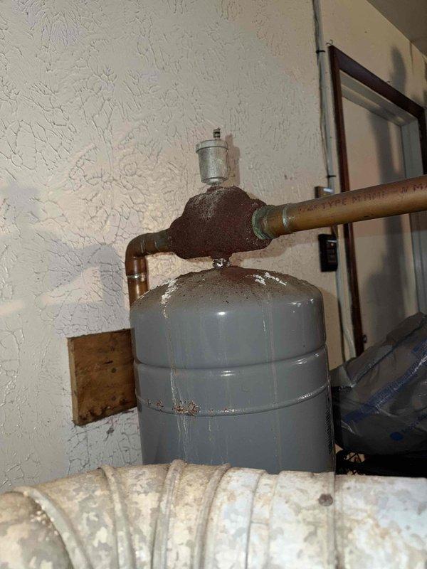 Inspected 30+ year old boiler system showing significant aging with rusted T-joint fittings and deteriorated components. Observed expansion tank with pressure gauge connection and examined copper piping network for potential repair needs. Documented system condition with photos to develop appropriate replacement/repair options as discussed with customer Bruno.