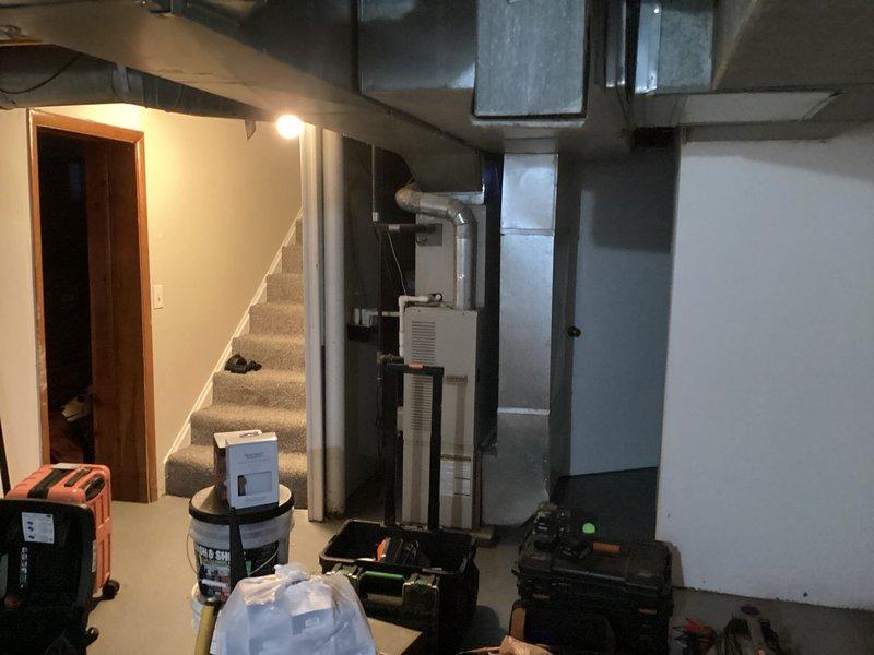 Performed initial assessment for potential HVAC system replacement at client's brother's residence. Inspected existing installation in basement, documenting current setup which includes galvanized ductwork with visible joints/seams and a rectangular air handler. System evaluation included examination of duct configuration, connections, and overall condition of the basement mechanical area where new equipment would be installed.
