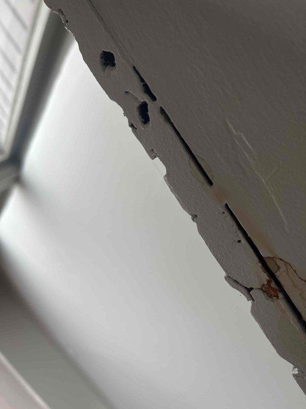 Investigated reported leak in floor suspected to be from radiant floor heating system. Inspection revealed damaged drywall with visible water damage and deterioration. Pressure gauge reading showed system pressure at approximately 60 PSI/400 kPa, which is within normal operating range, suggesting leak may be located elsewhere in the distribution system rather than in the pressure components.